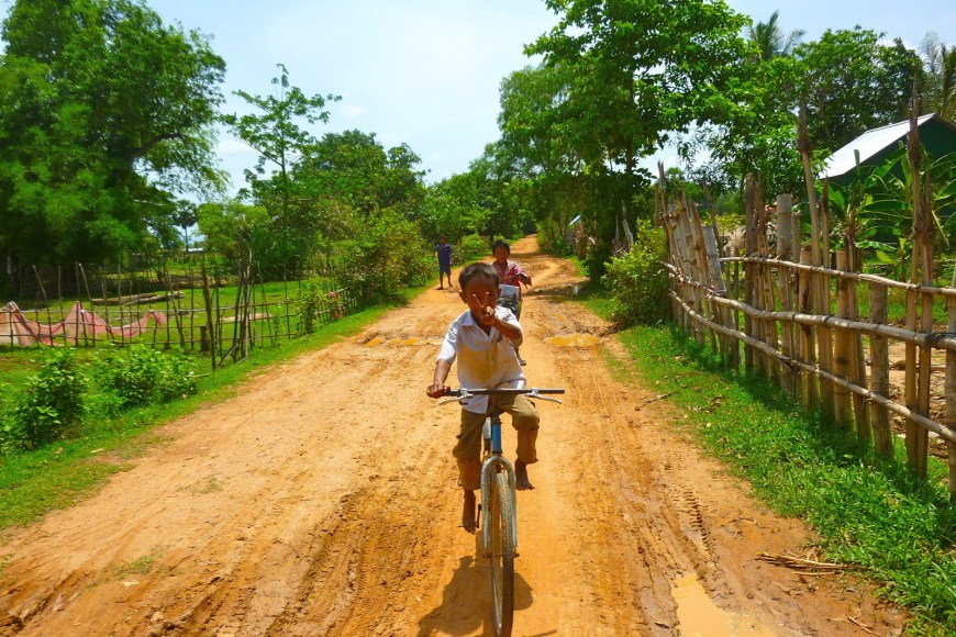 Happy Young Cambodian Boy Riding his Bike on a Dirt Road