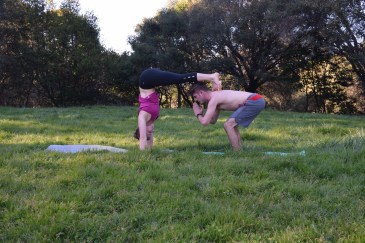 Active couple practicing partner yoga together in a grassy field
