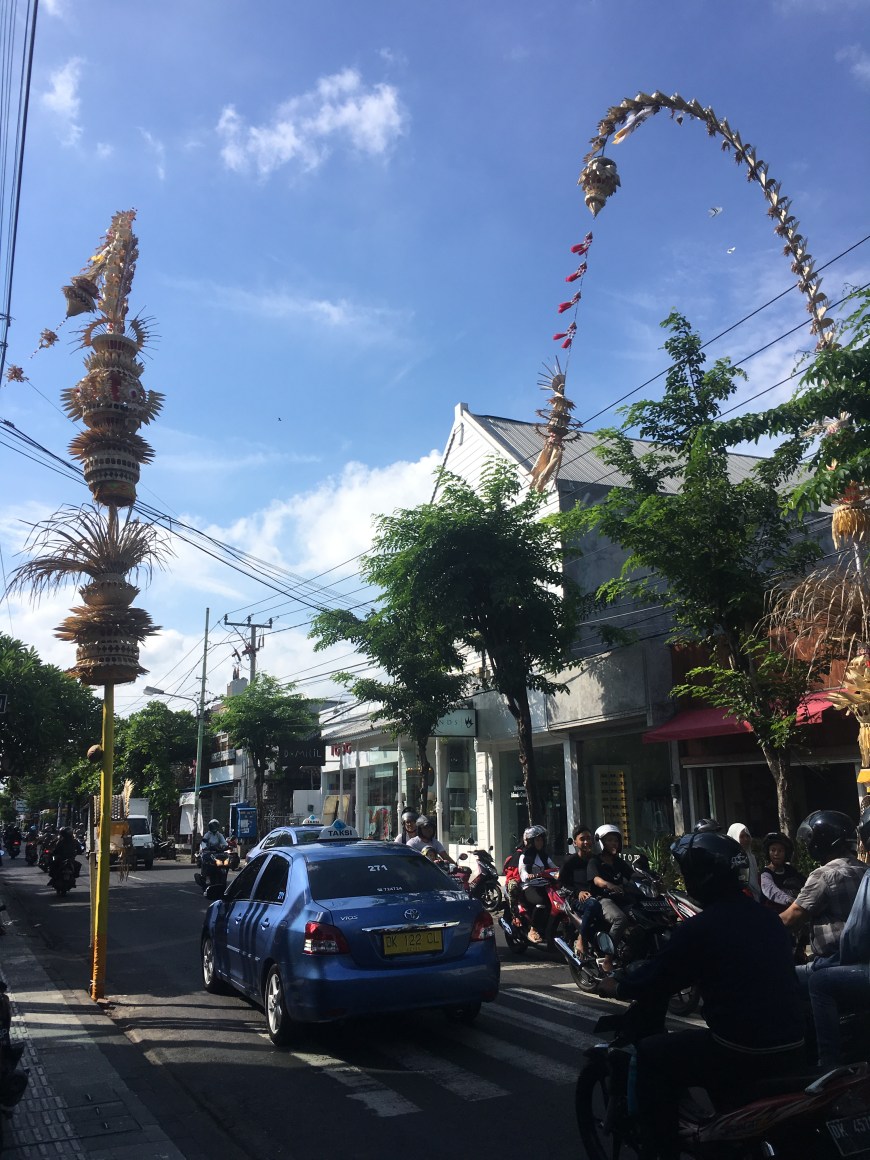 Street in Bali covered with scooters (mopeds) and a taxi