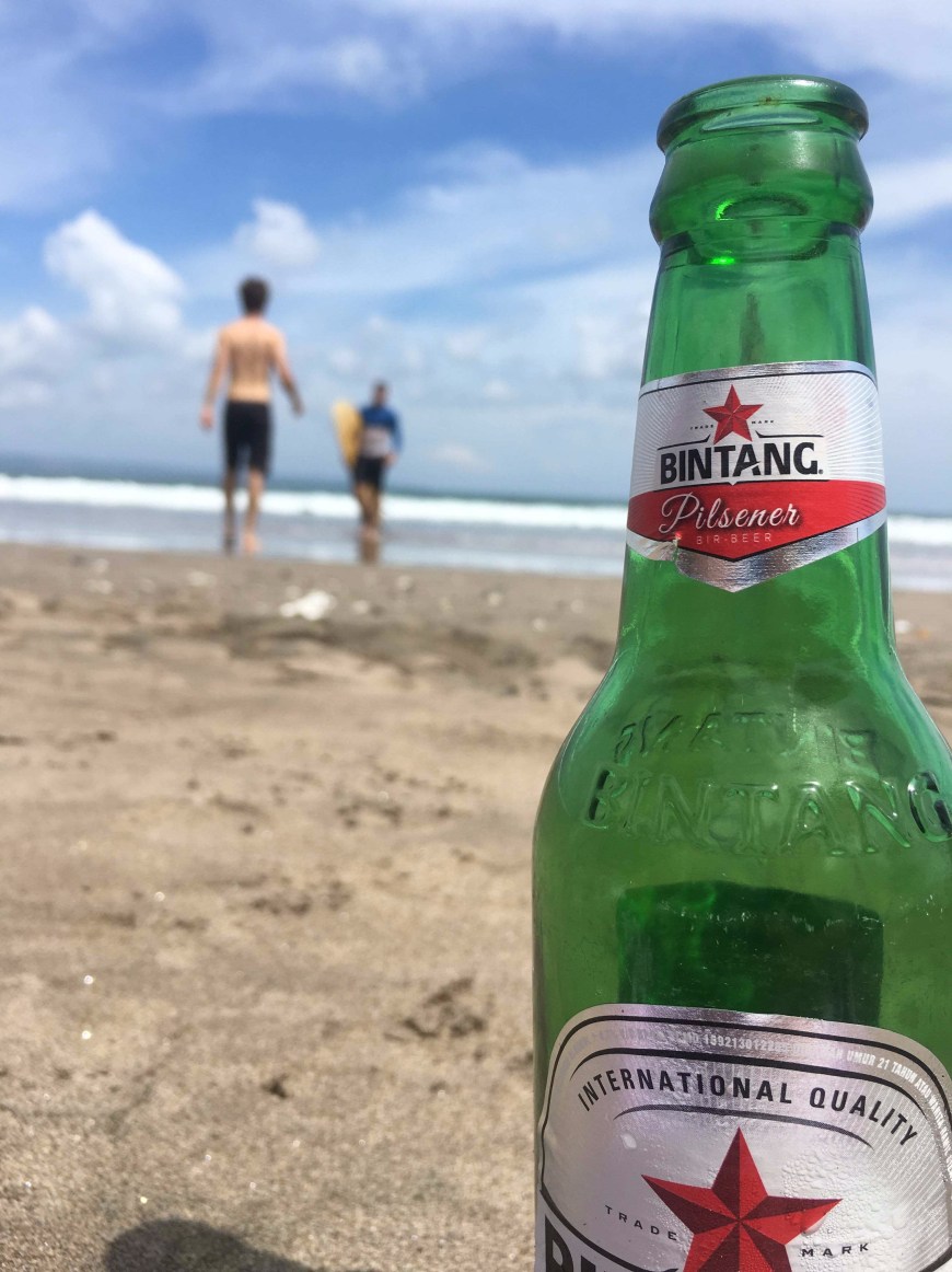 Enjoying a local Bintang on the beach in Seminyak, Bali, Indonesia with friends after a day of surfing