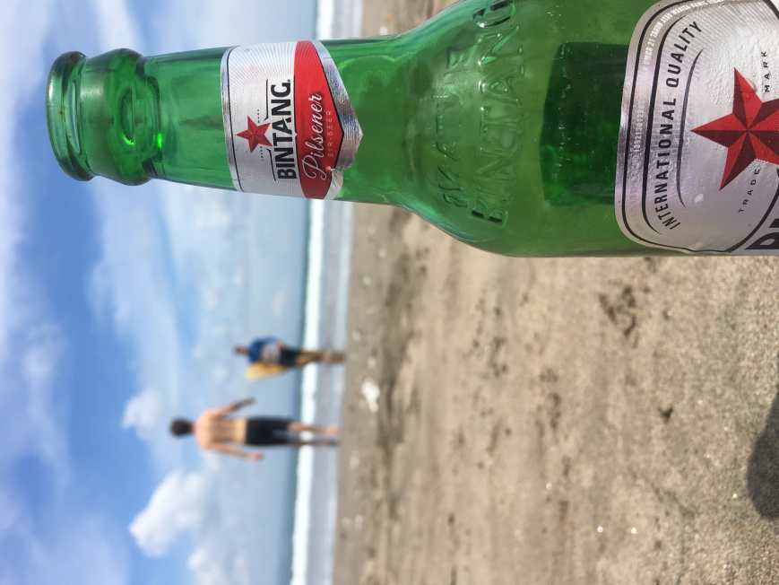 Enjoying a local Bintang on the beach in Seminyak, Bali, Indonesia with friends after a day of surfing