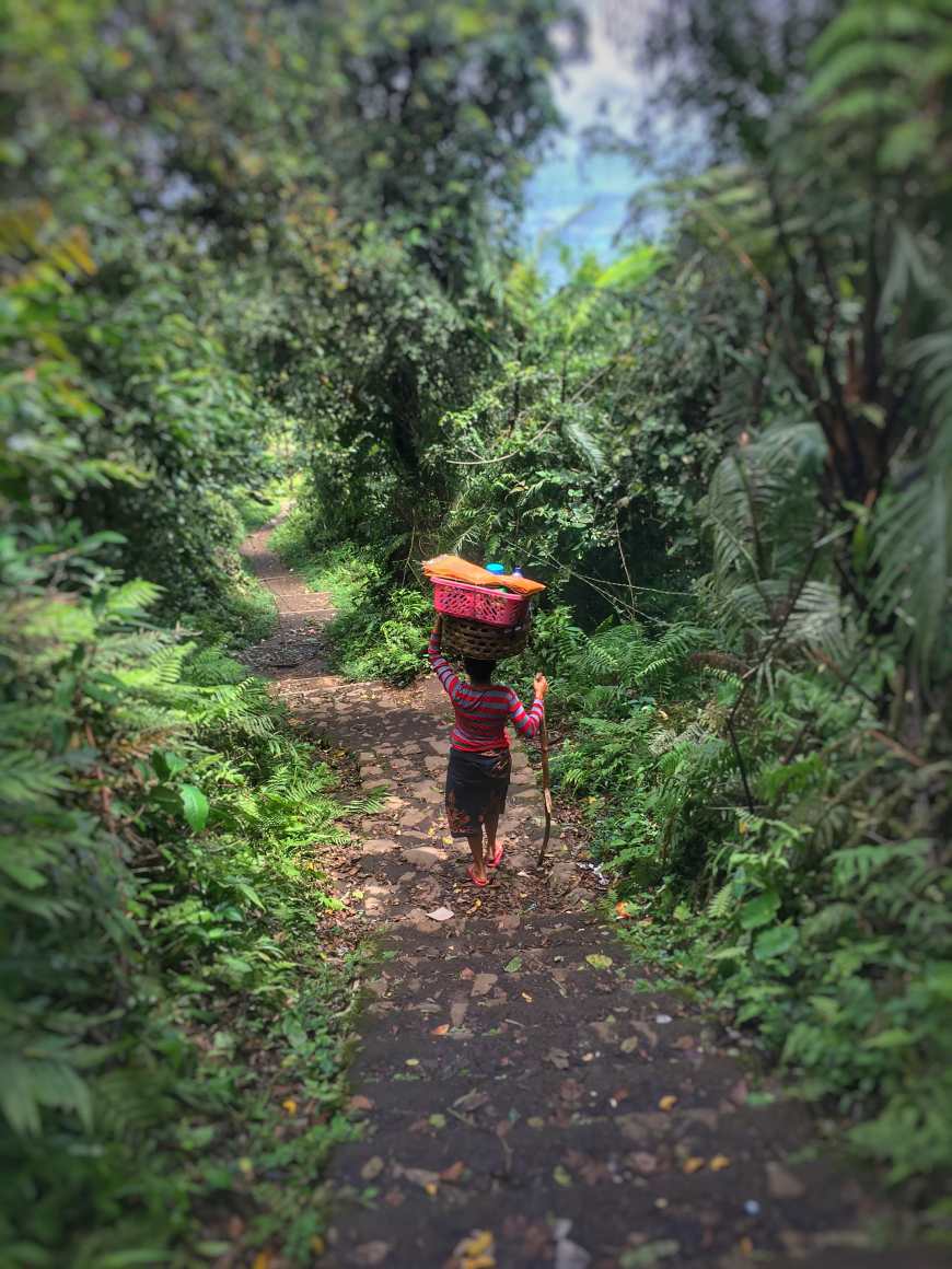 Woman climbing back down the mountainside with a basket on her head