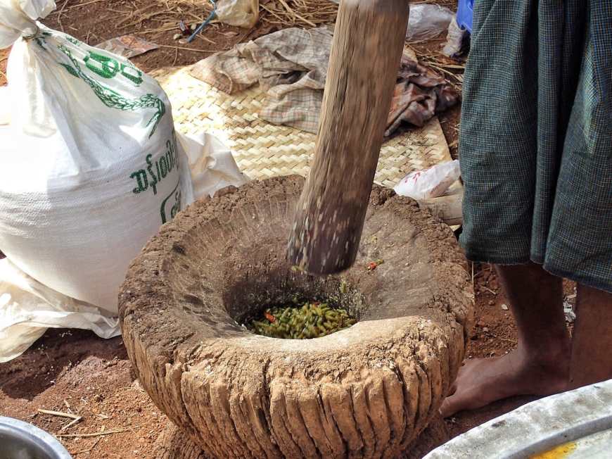 Mortar and pestle being used to make a spicy chili dish for a Burmese wedding