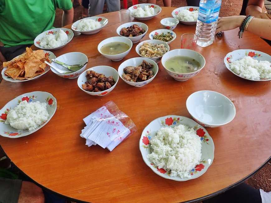 A table full of different Burmese dishes served family style at a Burmese wedding in a village