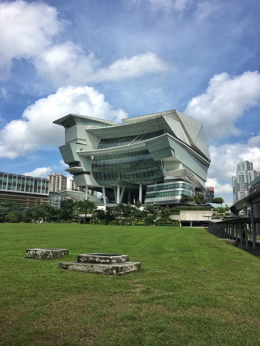 Futuristic looking building with a large grassy field in front and blue skies