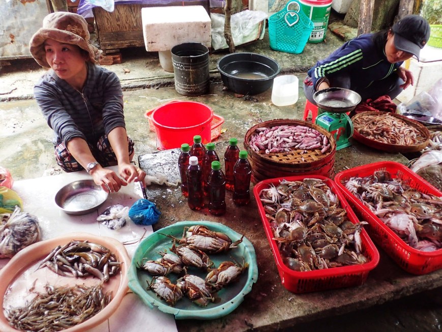 Woman selling crab and other seafood at a local market in Hoi An Vietnam