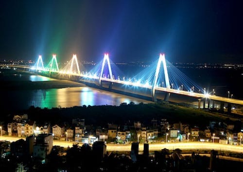 Hanoi's famous Nhat Tan Bridge at night illuminated by colored lights over the water