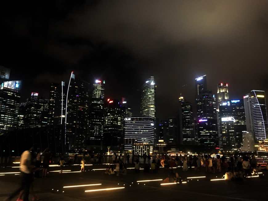 Sky scraper night scape in Singpore with people walking in the foreground