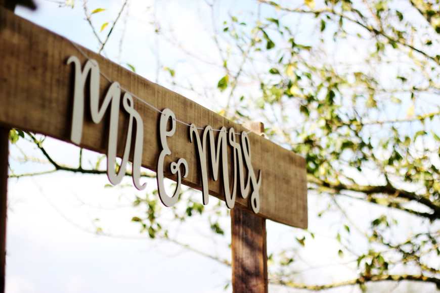 Mr & Mrs handing sign on a wooden archway with trees in the distance