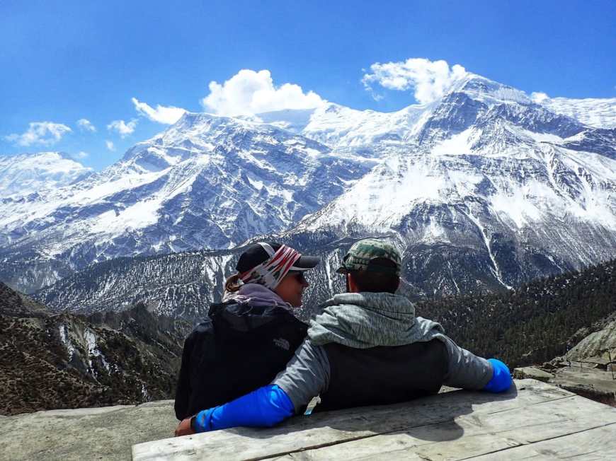 Travel bloggers, Alli & TJ Enjoying a trekking break to take in the vista of the Himalayan mountains
