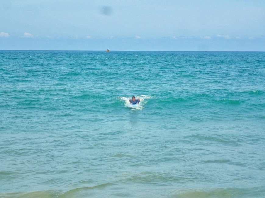 Travel and adventure blogger learning to surf and catching and small wave in Arugam Bay