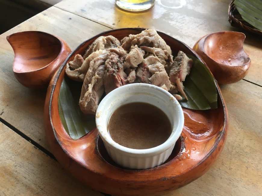 A plate of The Philippine's famous Lechon dish served in a wooden plate shaped like a pigs head