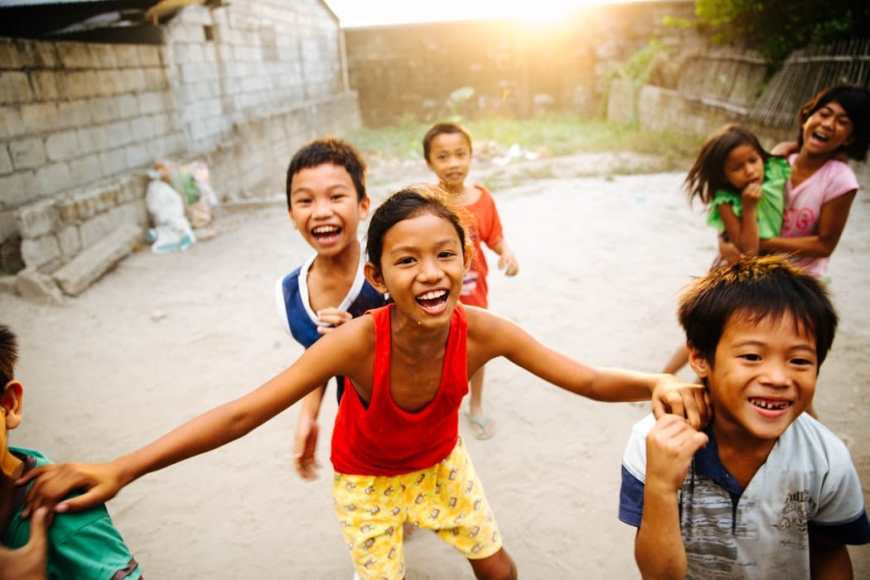 Group of filipino boys and girls laughing playing and smiling together as they look at the camera